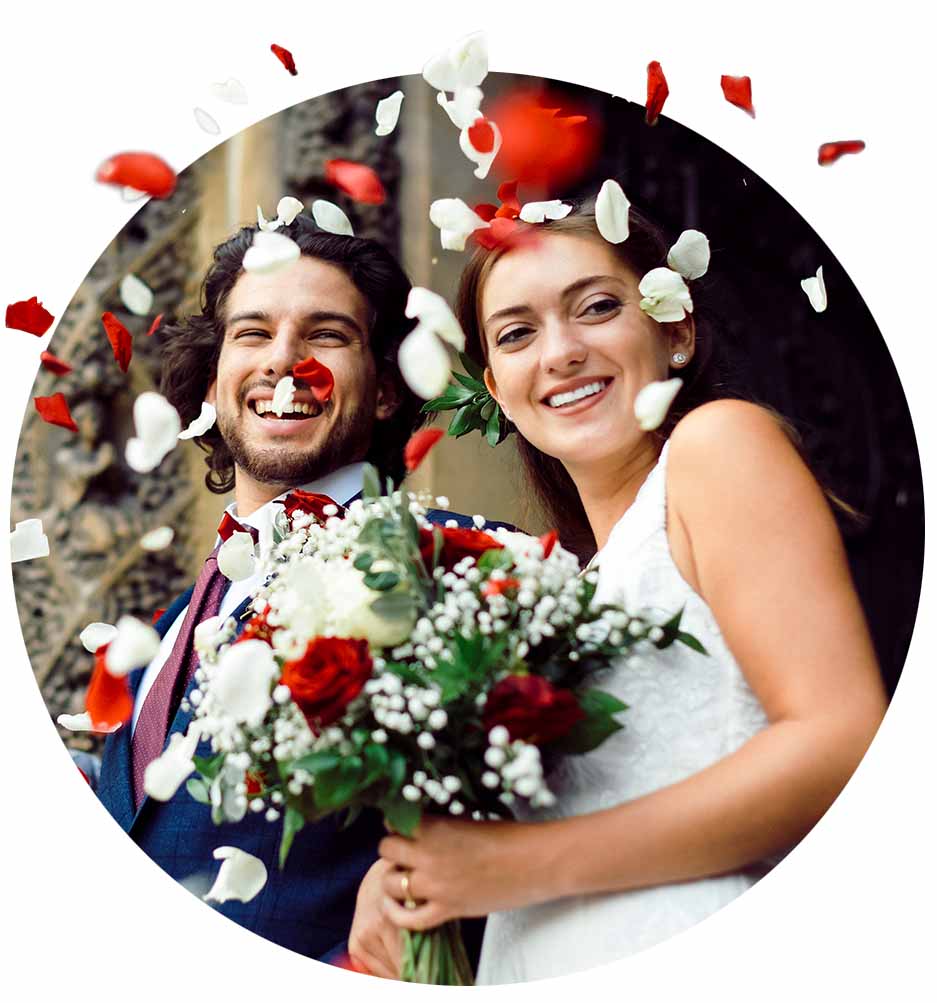 Newlyweds outside of church with flower petals falling around them.