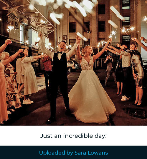 An image uploaded to the Hitched live streaming platform Bride and groom with hands in the air surrounded by friends and family holding sparklers.