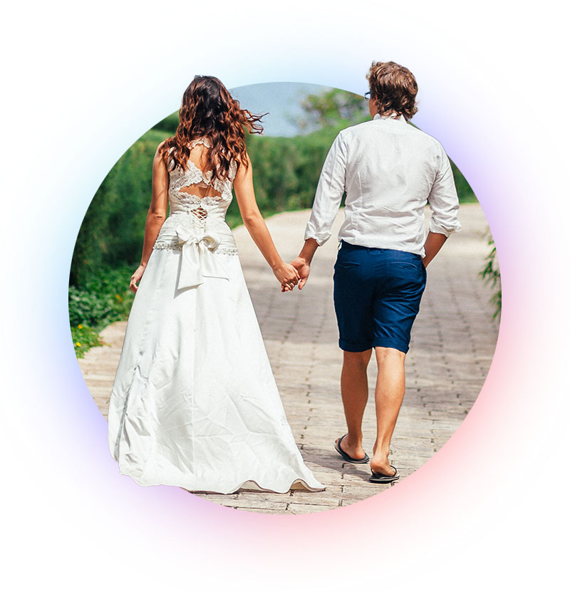 Rear view of newlywed couple walking down path.